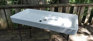 Stay cool at outdoor gatherings with the Old Cedar Outfitters Fill and Chill Ice Cooler Folding Table featuring a large sink and drain for easy cleaning. Perfect for camping, parties, or fish cleaning!